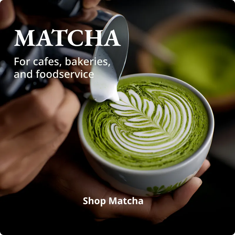 Matcha green tea latte with latte art being created, held by a person.