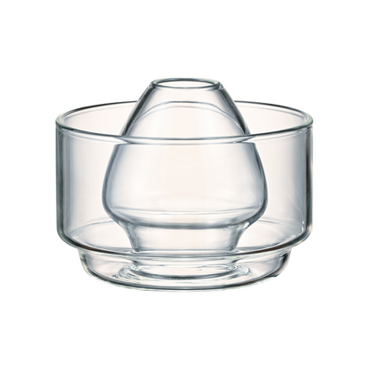 A clear, two-in-one heatproof glass matcha accessory by HARIO, featuring an inner chamber for soaking a whisk and an outer bowl design, isolated on a white background.